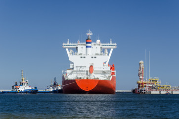 Fototapeta premium GAS CARRIER AND LNG TERMINAL - The big ship maneuvers in the mooring port at the wharf