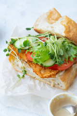 Sanwich with fried chicken on chiabatta with tomatoes, cheddar cheese, cucumber, onion, salad and microgreens