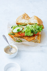 Sanwich with fried chicken on chiabatta with tomatoes, cheddar cheese, cucumber, onion, salad and microgreens