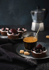 Coffee and chocolate cake with berries on a dark plate. Breakfast, coffee and dessert
