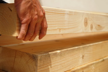 male Hand of carpenter is lifting Natural Wooden beam on construction site.