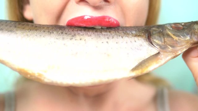 close-up. female lips with red lipstick with appetite eat big raw fish.