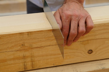 male worker hands sawing Natural Wooden beam using saw.  detail, carpenter hands at work with a saw.