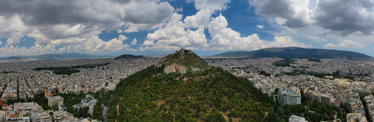 Fototapeta na wymiar Aerial panoramic photo of famous Lycabettus hill with iconic chapel of Saint George on top and beautiful clouds,Athens, Attica, Greece