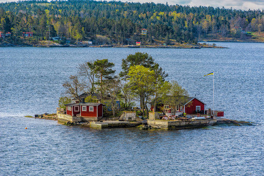 Picturesque summer houses painted in traditional falun red on dwellings island in Stockholms Skärgården (Stockholm Archipelago) in Baltic sea at spring sunny morning.