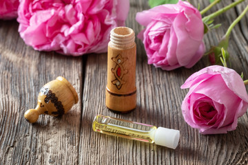 A bottle of rose essential oil with rose flowers