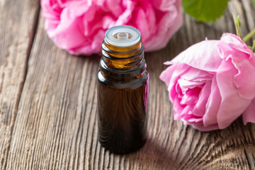 A bottle of rose essential oil with rose flowers