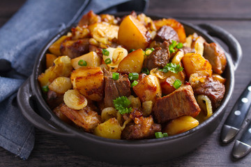 Tasty food: succulent beef with fried potatoes, onion and garlic. Country-style roasted potatoes with meat