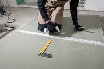 Worker is using a polyurethane foam for gluing drywall at ninety degrees. Hand holding polyurethane expanding foam glue gun applicator