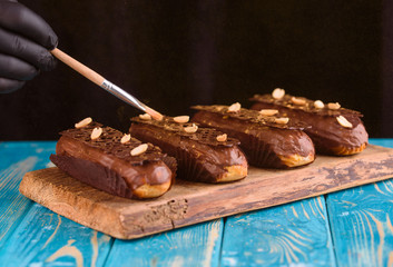 Delicious chocolate and peanut eclairs on a blue wooden table