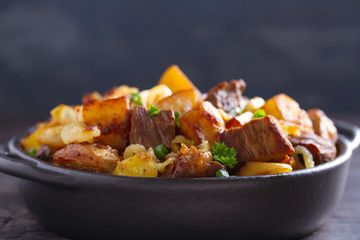 Tasty food: succulent beef with fried potatoes, onion and garlic. Country-style roasted potatoes with meat