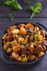 Tasty food: succulent beef with fried potatoes, onion and garlic. Country-style roasted potatoes with meat