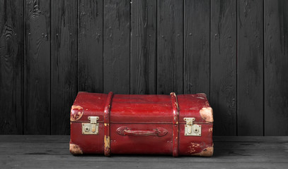 vintage red suitcase on a black wooden background