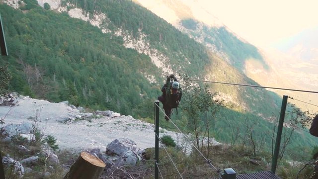 SLOW MOTION Tandem ride on a zipline cable in the heart of Julian Alps. Young adrenaline seeking couple on a zipline adventure