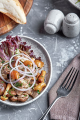 marinated mushrooms and onions in a plate on a grey background