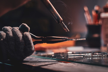 Closeup photo shoot of of soldering using pliers and peace of glass.