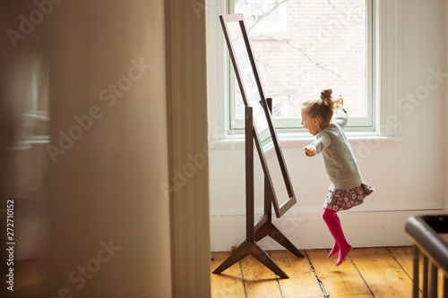 Side view of cheerful girl jumping in front of mirror