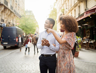 Fototapeta premium Couple with mobile phone searching direction while standing on street in city