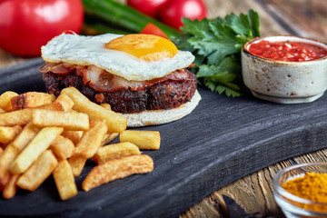 Beef steak with egg and salad from greens and vegetables. Wooden background, table setting, fine dining