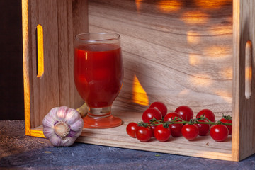 Glass of tomato juice, cherry tomatoes, red paprika on kitchen table. Cement background. Copy...