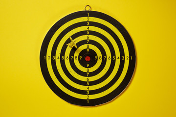 Yellow arrow dart hitting the target dartboard