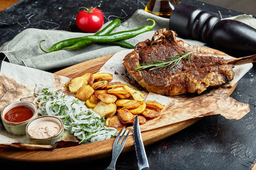 Tomahawk steak with vegetables and a knife on the table. Grilled meat with grilled vegetables and fresh vegetables on the table.