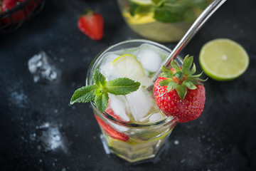 Detox water or mojito with lime, strawberry in glass. Summer healthy freshness drink. Close up.