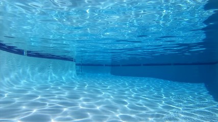 Empty suburban swimming pool with underwater sunlight patterns.