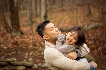 Obraz premium Father carrying cute happy daughter while standing in forest