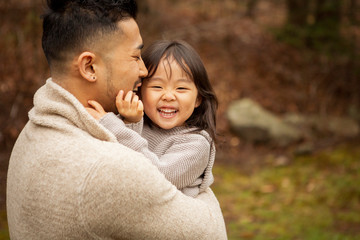 Fototapeta premium Happy father carrying cute daughter while standing in forest