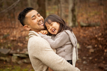 Obraz premium Smiling father carrying his daughter in forest