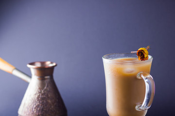 Copper coffee pot (Cezve) and coffee beans. Coffee with milk on dark background. Latte and black chocolate on slate board. Milk drink in glass beaker and dried rose