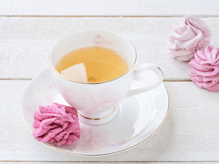 GREEN TEA WITH MINT AND MARSHMALLOWS ON WHITE WOODEN BACKGROUND
