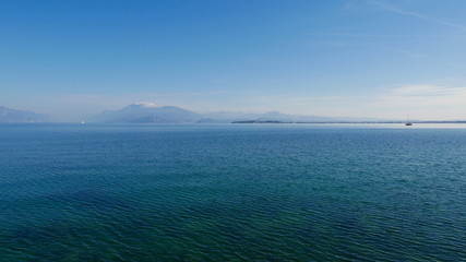Fototapeta premium The blue waters of Lake Garda stretching up to the horizon. A popular destination for turistic trips to Italy.