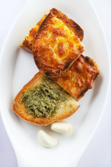 Toasts with garlic and cheese and pesto. On a white background. Close up. Selective focus.