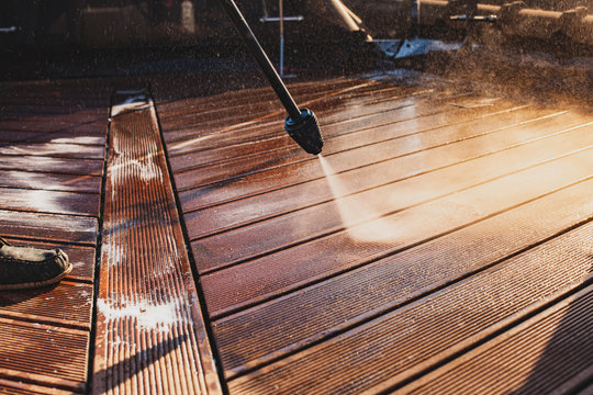 Man Cleaning Terrace With A Power Washer - High Water Pressure Cleaner On Wooden Terrace Surface