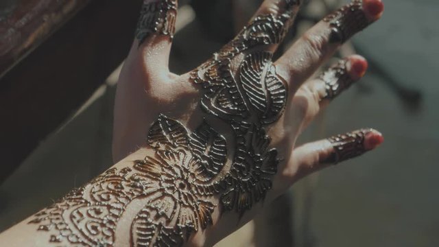 Transition to a woman's hand in the sunlight showing off her traditional henna tattoo