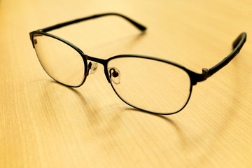 Selective focus eyeglasses on the wooden table background, glasses placed on the table