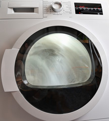 Closed clothes dryer door with spinning laundry.