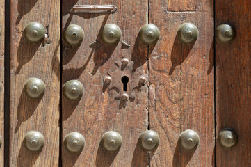 Keyhole in an old paneled wooden door with antique door handle; rusty and weathered