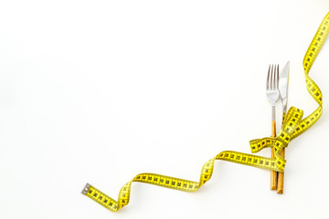 Fork and knife near measuring tape on white background top view space for text