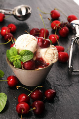 Cherry and vanilla ice cream scoop with fresh cherries and mint on a rustic background