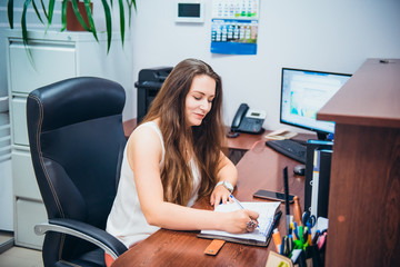 Young caucasian business lady sitting on her workplace in office. Female entrepreneurship. Portrait...