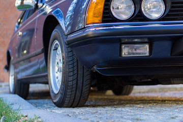 Blue vintage car standing on the pavement at sunset