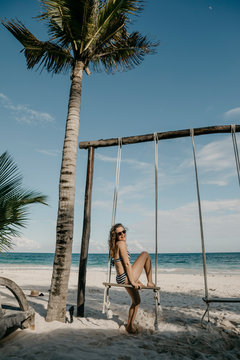Mexico, Quintana Roo, Tulum, happy young woman on a swing on the beach