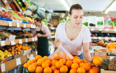 Woman customer choosing fresh oranges  on the supermarket