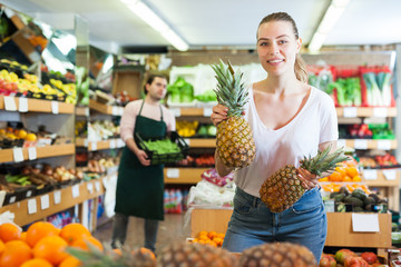 Young female  holding  fresh pineapples  in fruit store
