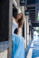 Girl model is sitting in the wooden-stone wall in old European city and looking up