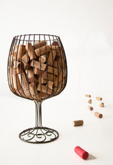 Corks from the bottles inside a vase simulating a glass of wine and some cork stoppers next to the vase with a white background