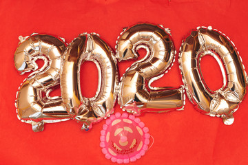 2020 ballon numbers isolated on red background with pink hat, new year concept